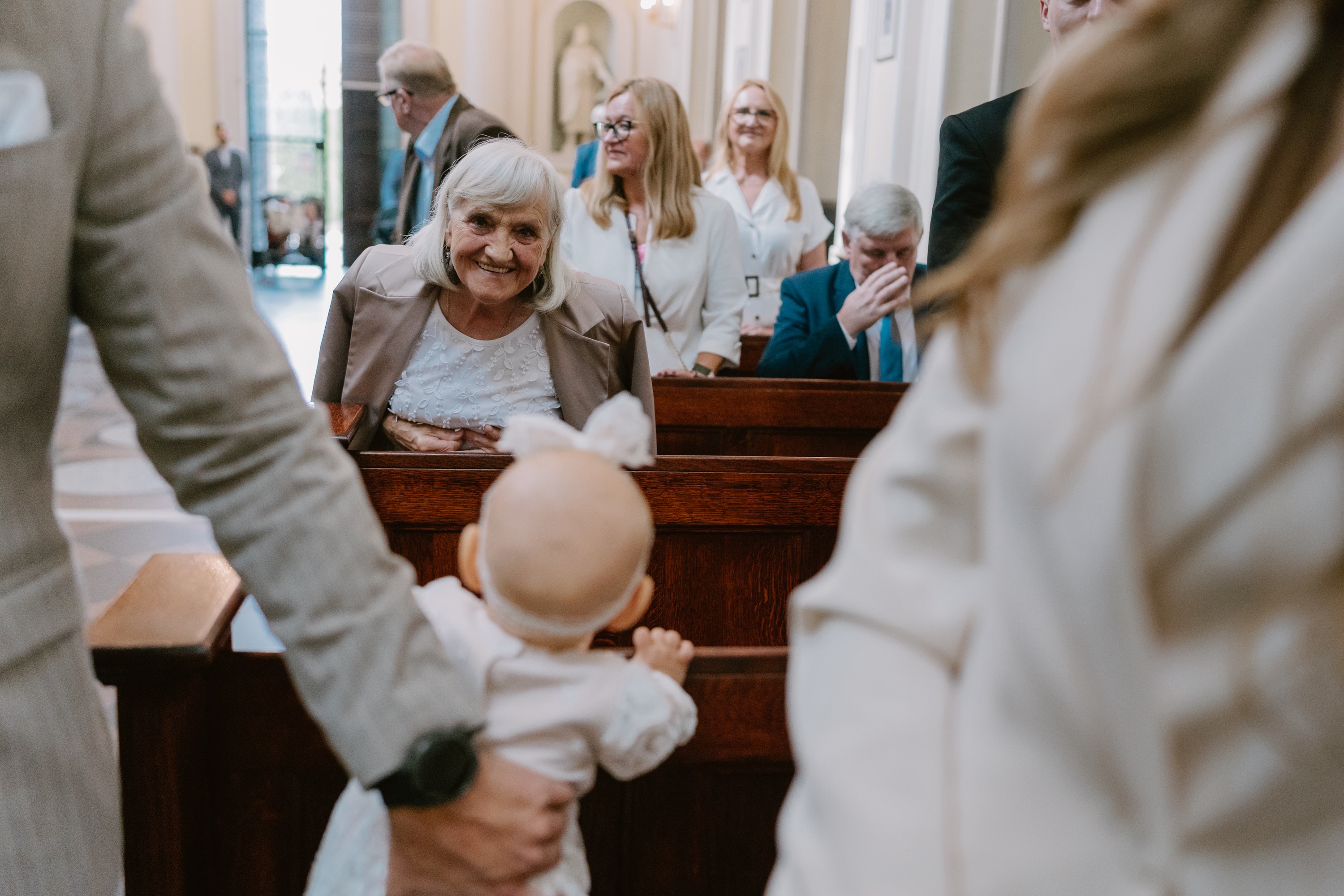 Babcia uśmiecha się do niemowlęcia w kościelnej ławce podczas chrztu